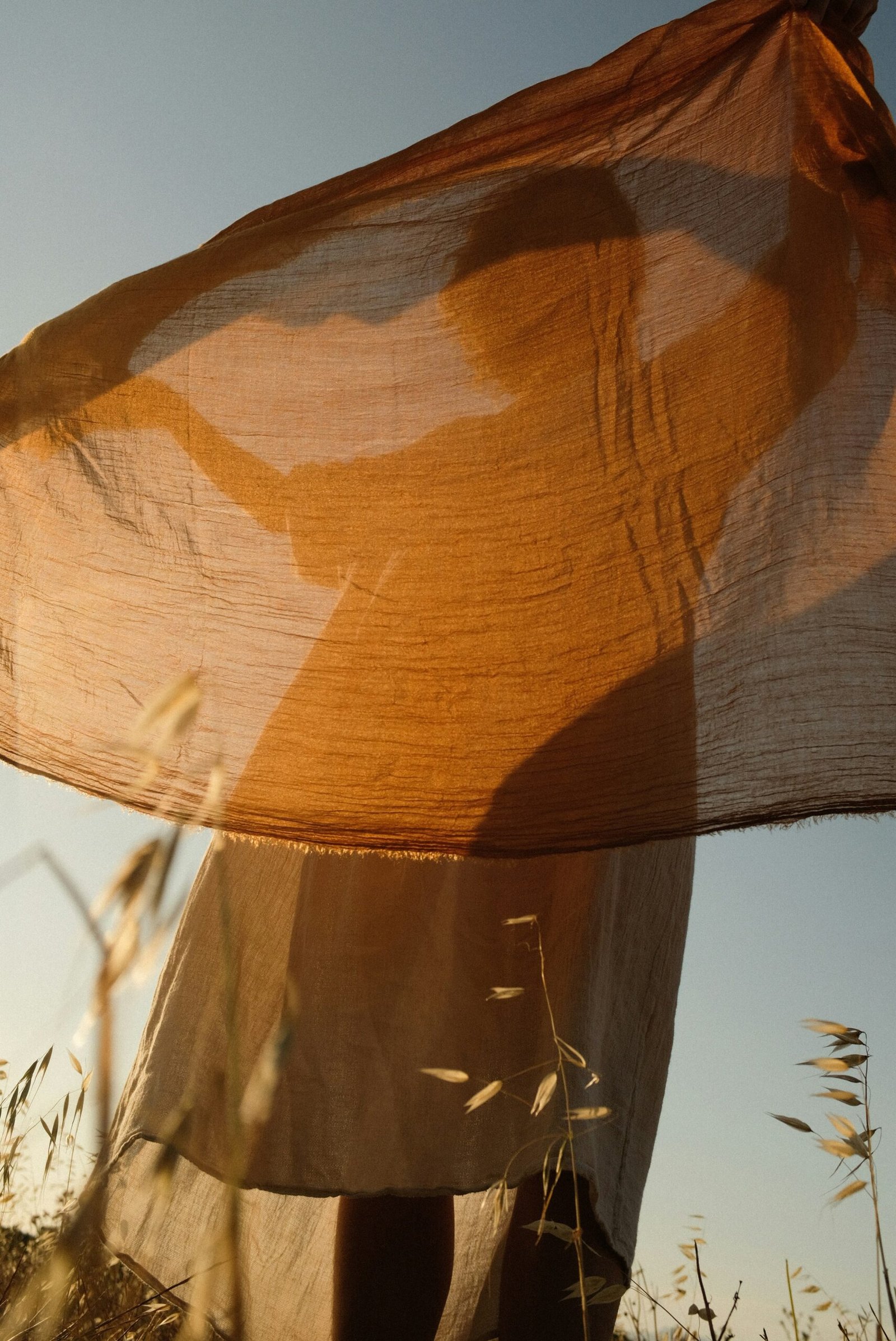 a woman standing in a field holding a scarf